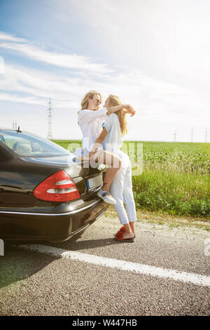Young lesbian's couple kissing before vacation trip on the car in sunny