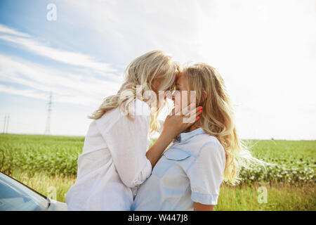 Young lesbian's couple kissing before vacation trip on the car in sunny