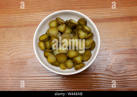 Sliced gherkins cucumbers in a bowl on a wooden table Stock Photo