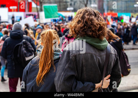 Two young people are seen from the back, watching a crowded demonstration of people against global warming on a street in Montreal, Canada Stock Photo