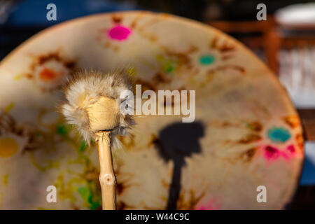 A close-up view of a sacred drum and drumstick, traditionally used by Native American tribes for spiritual ceremonies. Traditional percussion instrument. Stock Photo