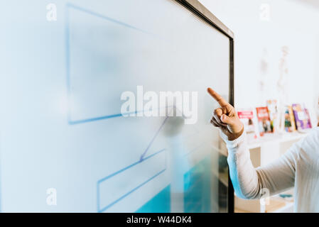Teacher explaining some ideas on a touch TV to his students. Stock Photo