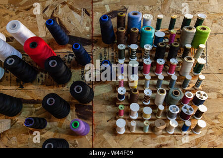 A close-up view of various colored thread spools, pinned and organized on an OSB wall inside an atelier for easy access. Stock Photo