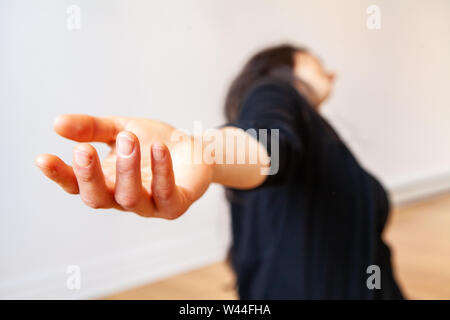 A lady's hand is viewed close up, as she stretches her blurry body away from the camera during expressive dancing alone, copy space to the right Stock Photo