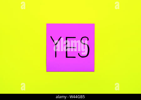 Reminder, combination of colour, choice concept - Close up black handwritten inscription yes word on one purple square sticker on yellow background wi Stock Photo