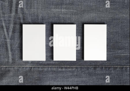 Mockup of three blank vertical business cards on gray denim background. Copy space for text. Flat lay. Stock Photo