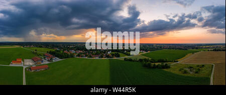 A drone shot of a sunset of a town, while rain clouds are coming. Stock Photo