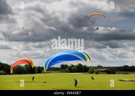 Paramotoring club with kiting practise on the ground with and without motor and an airborne pilot coming in for a landing in Hungerford England Stock Photo