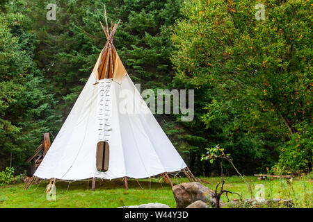 A rustic tipi tent is viewed by woodland, similar to that of Native American tribes, during a festival fusing ancient culture with modern music. Stock Photo