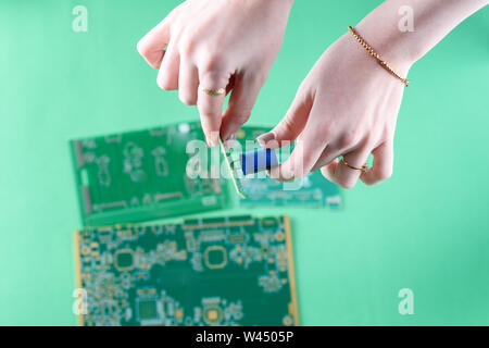 The woman technician is assembling a capacitor on the Circuit Board. The concept of computer, service, electronics, hardware, repairing, upgrade and t Stock Photo