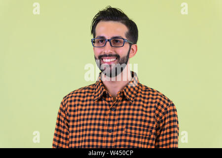 Face of happy young bearded Persian hipster man thinking Stock Photo