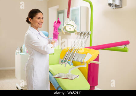 Beautiful smiling Caucasian female doctor wearing aseptic gloves Stock Photo
