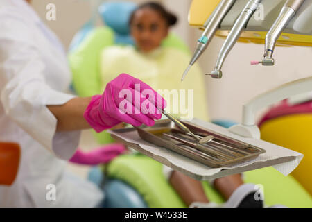 Female dentists hands in gloves holding a mirror Stock Photo