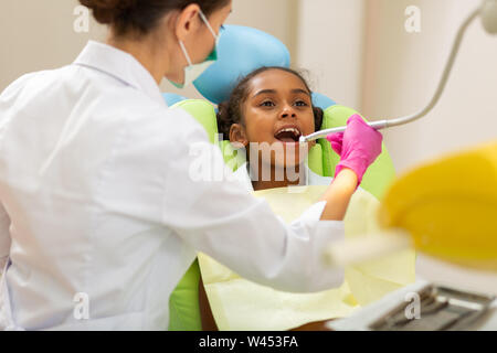 Dark-haired woman doctor leaning over a young patient Stock Photo