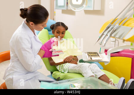 Dark-haired female doctor brushing an artificial teeth model Stock Photo
