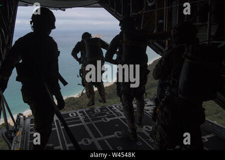 U.S. Air Force Special Tactics Airmen assigned to the 22nd Special Tactics Squadron, Joint Base Lewis-McChord, Washington, exit a C-130H Hercules aircraft during static line jump training at a range on Marine Corps Base Hawaii, June 24, 2019. Special Tactics Airmen train to land safely in a planned drop zone and conduct their mission, whether it be personnel recovery, airfield reconnaissance and establishment or special operations air integration. (U.S. Air Force photo by Staff Sgt. Rose Gudex) Stock Photo