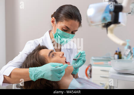 Woman doctor in a mask leaning over a patient Stock Photo