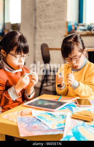 Curious little girls with mental issues pulling out tongues Stock Photo