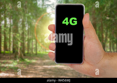 4G word written in a smartphone against a forest. Stock Photo