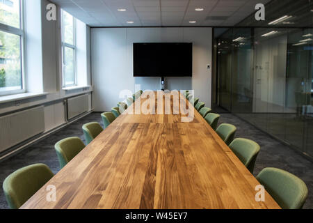 Meeting room or Board room with empty presentation LCD screen at the head of the table in modern office. Office closed work from home coronavirus. Stock Photo