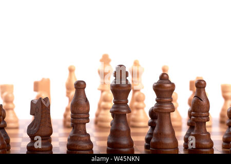 Row of white and black wooden chess pieces on a chessboard, with selective focus, isolated on white background. Stock Photo