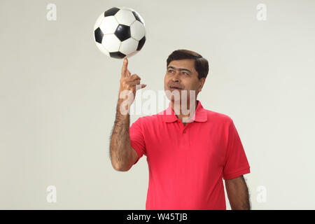 Man balancing a soccer ball on his finger Stock Photo