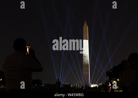 Washington DC, USA. 19th July 2019. In honor of Apollo 11's 50th anniversary, an audience member captures the moon as projected on the east side of the Washington Monument. Credit: Tim Thulson/Alamy Live News. Stock Photo