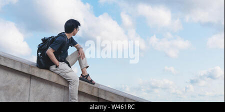 a man with backpack looking at blue sky and white clouds in summer Stock Photo