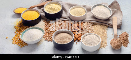 Various gluten free flour - chickpeas, rice, buckwheat, quinoa, almond, corn, oatmeal on grey background. Panorama, banner Stock Photo