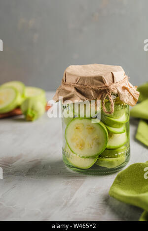 Fermented zucchini in a jar on a light background close-up copy space. Harvesting vegetables for healthy food. Stock Photo