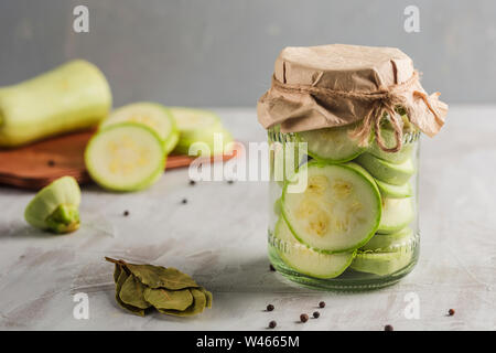 Fermented zucchini in a jar of spices on a light background close-up with copyspace. Harvesting vegetables for healthy food. Stock Photo