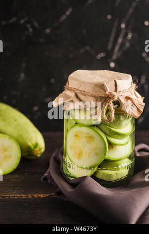 Fermented the zucchini in a jar on a dark background closeup with copyspace. Harvesting vegetables for healthy food. Stock Photo