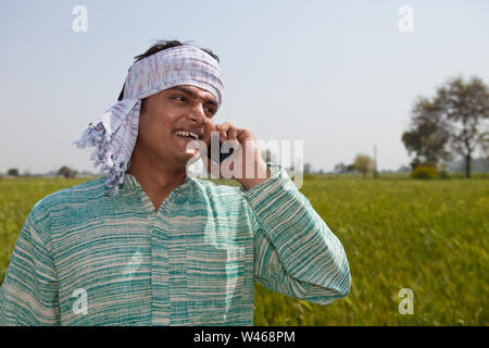 Farmer talking on mobile phone in a field Stock Photo