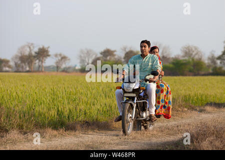 Rural couple riding on a motorcycle in the field Stock Photo