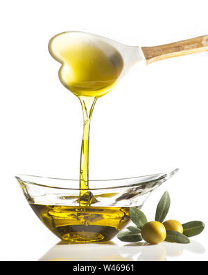 in a transparent crystal bowl flows extra virgin olive oil poured from a spoon with the shape of a heart Stock Photo