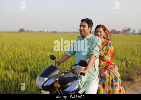 Rural couple riding on a motorcycle in the field Stock Photo