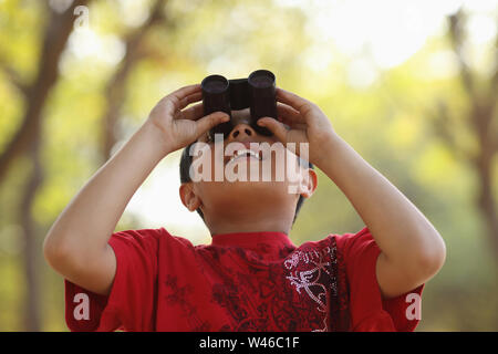 Boy looking through binoculars Stock Photo