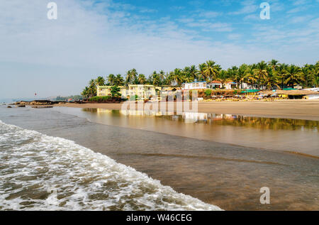 Guesthouses and sunbeds on beach of Arabian Sea in middle of rocks and sandstone in Ashvem, Goa, India Stock Photo