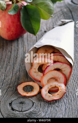 Dehydrated apples chips in paper bag on rustic table Stock Photo
