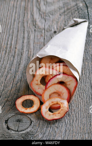 Dehydrated apples chips in paper bag on rustic table Stock Photo