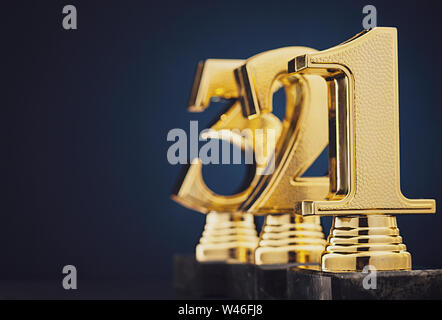 Close up view of three separate slightly blurry golden number trophies in front of dark blue gradient background Stock Photo