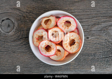 Dehydrated apples chips in wooden bowl on a wooden table, top view Stock Photo