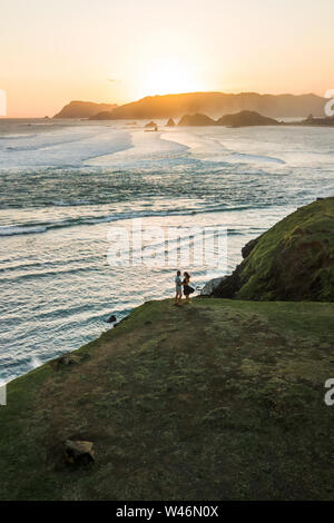 Happy couple enjoying sunset with amazing ocean and mountain view on Merese Hill on Lombok, Indonesia. Aerial drone shot. Stock Photo