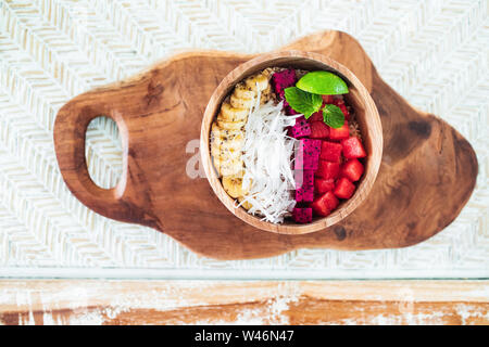 Fresh tasty smoothie bowl with dragon fruit, red watermelon, banana, coconut flakes and slice of lime. Healthy vegetarian natural breakfast. Served in Stock Photo
