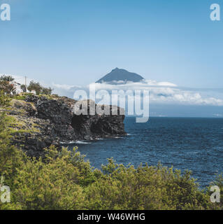 Mount Pico volcano western slope viewed from ocean with summit in clouds, seen from Faial Island in Azores, Portugal. Stock Photo