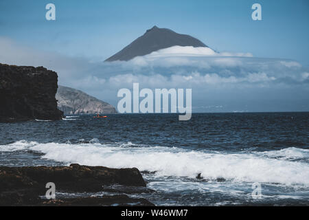 Mount Pico volcano western slope viewed from ocean with summit in clouds, seen from Faial Island in Azores, Portugal. Stock Photo