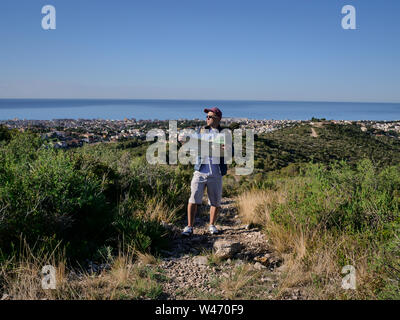 Male tourist with a map of the area stands on a stone path Stock Photo