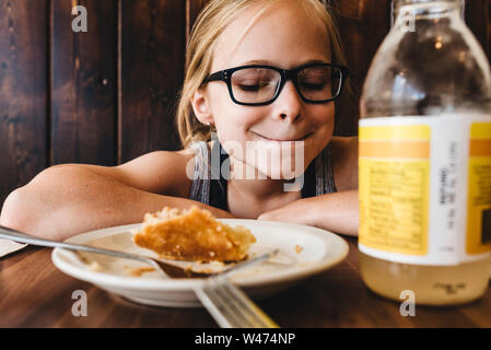 Little girl eats and drinks at table in cafe restaurant Stock Photo