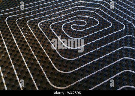 Black underfloor heating surface with heating pipes. Stock Photo