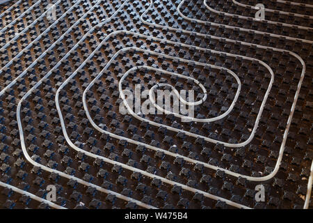 Black underfloor heating surface with heating pipes. Stock Photo
